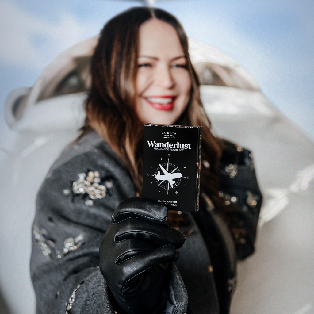Kristi Moe holding a 'Wanderlust' perfume passport product box with a scenic background