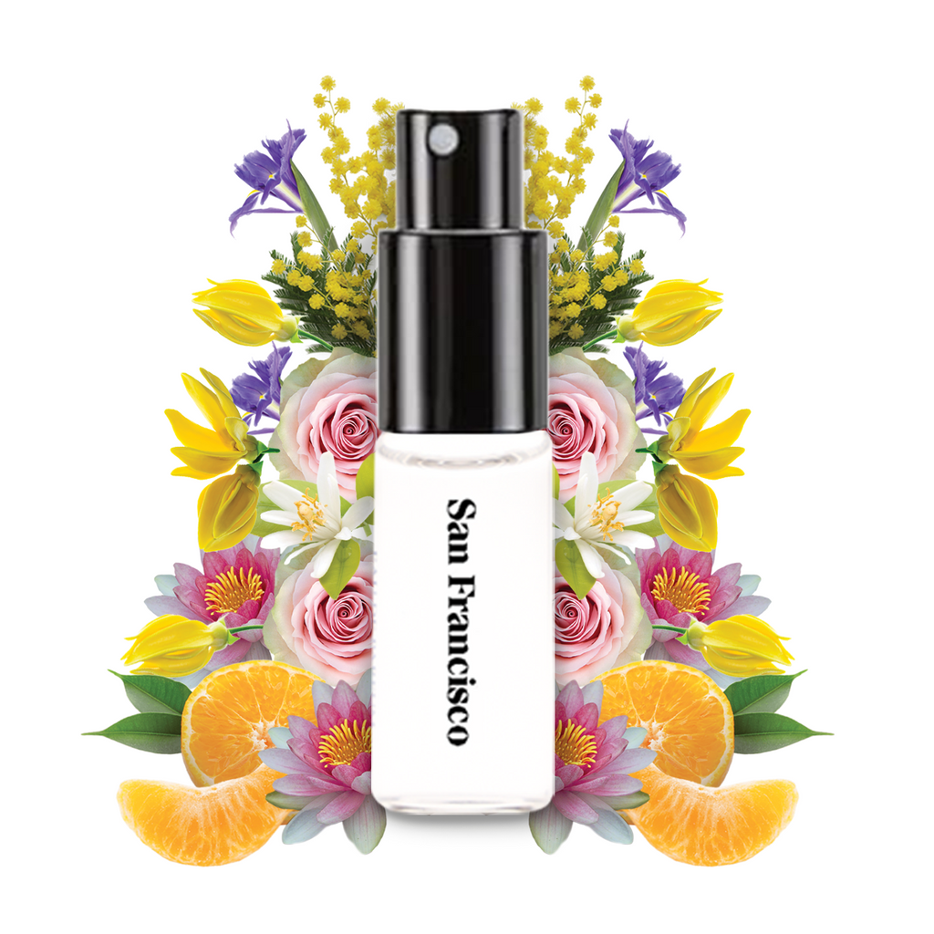 Wanderlust San Francisco perfume 2ml spray bottle surrounded by flowers, orange slices, and green leaves on a white background.